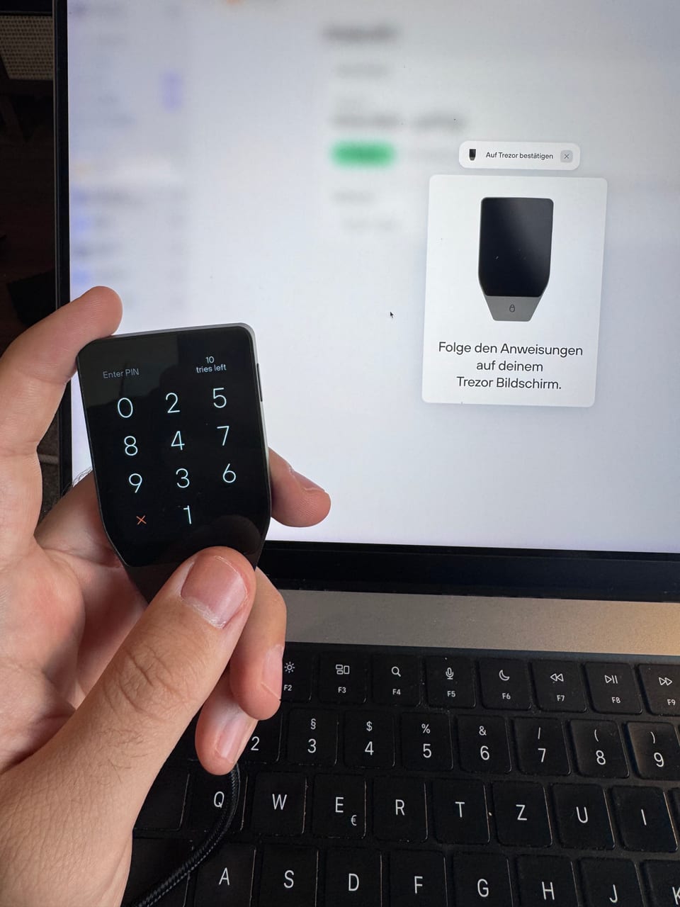 Die PIN-Eingabe auf dem Touchscreen, dahinter die Trezor Suite